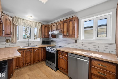 Kitchen with wood-finish cabinetry, light wood-finish countertops, and white subway tile backsplash - 6203 90 Avenue, Edmonton, AB 