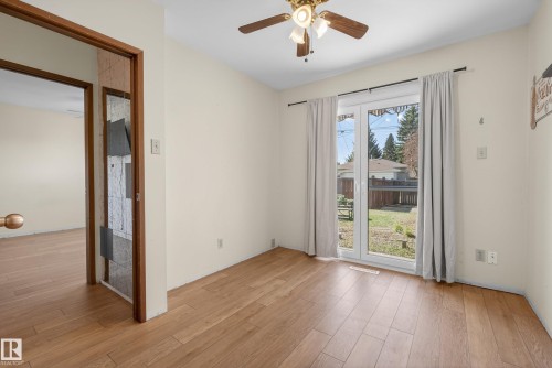 Room featuring wood-finish flooring, a ceiling fan with light fixture, and white walls - 6203 90 Avenue, Edmonton, AB 