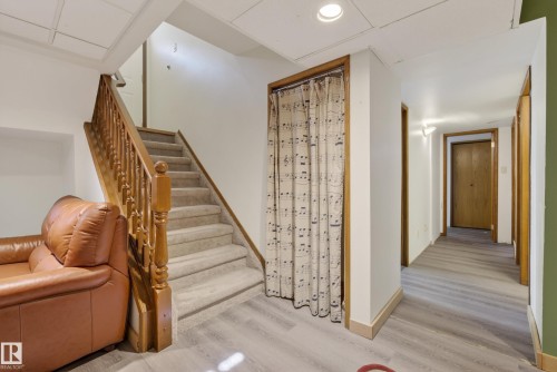 Carpeted staircase with wood railing, wood-finish flooring, recessed ceiling lighting, and a closet with a fabric door covering - 6203 90 Avenue, Edmonton, AB 
