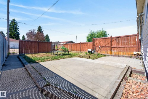 Expansive backyard featuring a combination of concrete patio space and a grass lawn, enclosed by a wood privacy fence - 6203 90 Avenue, Edmonton, AB 