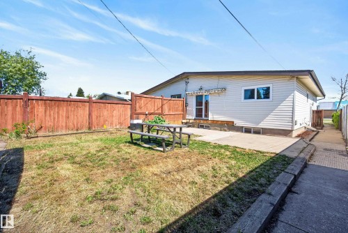 Fenced backyard featuring a concrete patio, a wood deck, and an exterior door with an awning - 6203 90 Avenue, Edmonton, AB 