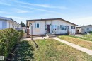 Single-story residence featuring light-colored siding, a brown trim roofline, and a prominent bay window - 6203 90 Avenue, Edmonton, AB 