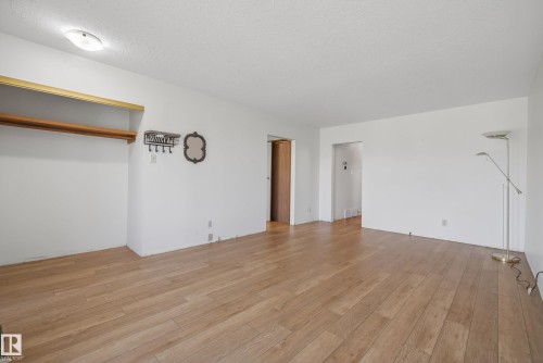 Spacious interior room featuring wood-finish flooring, white walls, and a built-in closet with a top shelf and hanging rod - 6203 90 Avenue, Edmonton, AB 
