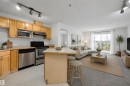 Open-concept living area featuring a kitchen with light wood cabinetry and stainless steel appliances - 320 245 Edwards Drive, Edmonton, AB 