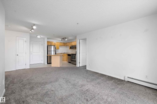 Open-concept living space featuring gray carpet flooring and white walls - 320 245 Edwards Drive, Edmonton, AB 
