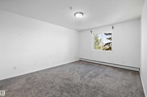 Carpeted room with white walls, a single window, and a flush-mount ceiling light fixture - 320 245 Edwards Drive, Edmonton, AB 