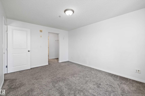 Neutral-toned carpet flooring complementing white walls and trim - 320 245 Edwards Drive, Edmonton, AB 