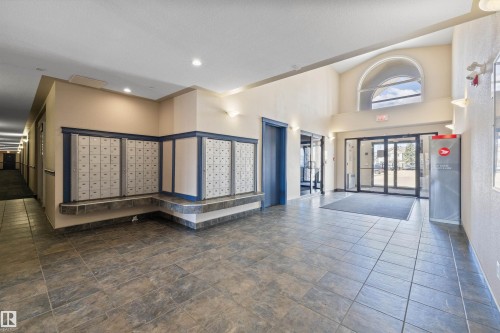 Spacious lobby featuring large format tile flooring, a high vaulted ceiling with an arched window, and recessed lighting - 320 245 Edwards Drive, Edmonton, AB 