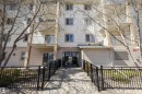 Multi-story building featuring light-colored siding, multiple balconies with white railings, and a ground-level entrance - 320 245 Edwards Drive, Edmonton, AB 