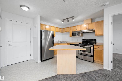 Kitchen featuring light wood cabinetry and stainless steel appliances - 320 245 Edwards Drive, Edmonton, AB 
