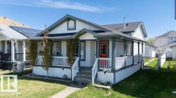 Single-story home featuring a full-width covered front porch, white siding, and dark trim - 