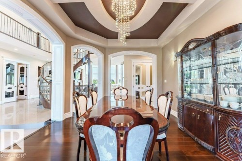 Dining area featuring dark wood-finish flooring, a tray ceiling with a chandelier, and arched doorways - 328 52327 Range Rd 233, Rural Strathcona County, AB 