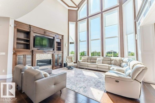 Two-story living area featuring a custom built-in entertainment center with a fireplace, dark wood-finish flooring, and a soaring vaulted ceiling - 328 52327 Range Rd 233, Rural Strathcona County, AB 