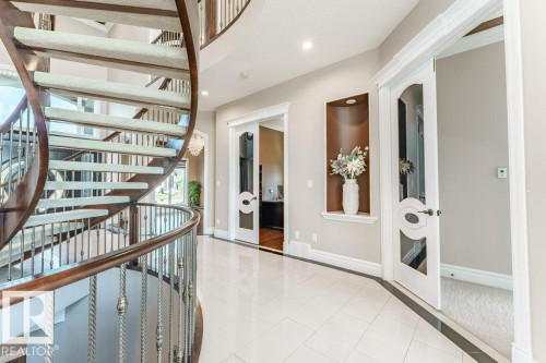 Grand entryway featuring a curved staircase with wood treads and wrought iron spindles - 328 52327 Range Rd 233, Rural Strathcona County, AB 