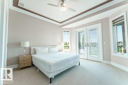 Bedroom featuring a tray ceiling with crown molding, ceiling fan, and light-toned carpeting - 328 52327 Range Rd 233, Rural Strathcona County, AB 