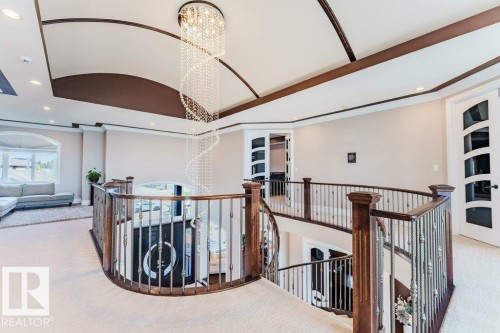 Grand foyer featuring a multi-story spiral crystal chandelier and a curved staircase with dark wood newel posts and wrought iron balusters - 328 52327 Range Rd 233, Rural Strathcona County, AB 