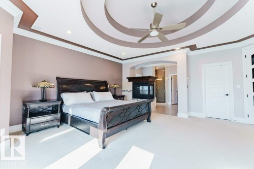 Recessed ceiling with decorative molding, ceiling fan, built-in fireplace with dark wood mantel, light-toned walls, and white paneled interior doors - 328 52327 Range Rd 233, Rural Strathcona County, AB 