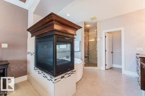 Corner fireplace with dark wood mantelpiece and decorative tile surround - 328 52327 Range Rd 233, Rural Strathcona County, AB 