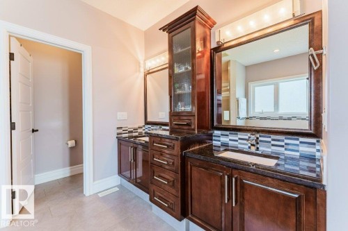 Dual vanity with dark wood cabinetry, integrated sinks, and dark countertops - 328 52327 Range Rd 233, Rural Strathcona County, AB 