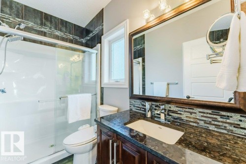 Bathroom featuring a dark wood vanity with a stone-finish countertop, undermount sink, and chrome faucet - 328 52327 Range Rd 233, Rural Strathcona County, AB 