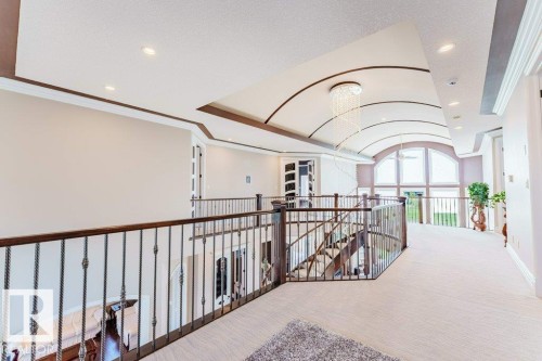 Upper-level landing featuring a vaulted ceiling with recessed lighting, an elegant chandelier, and an arched window - 328 52327 Range Rd 233, Rural Strathcona County, AB 