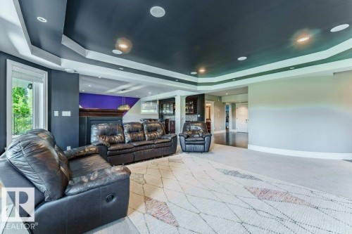 Spacious interior featuring a coffered ceiling with recessed lighting, large windows, a built-in wet bar, and a fireplace with a wood mantel - 328 52327 Range Rd 233, Rural Strathcona County, AB 