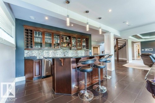 Custom bar area with dark wood cabinetry and glass-front upper storage - 328 52327 Range Rd 233, Rural Strathcona County, AB 