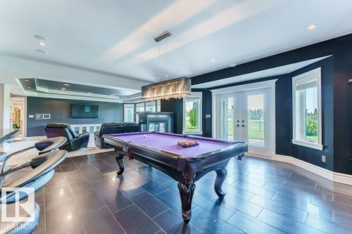 Spacious recreation room featuring dark tile flooring, a detailed tray ceiling, and a fireplace with a dark surround - 328 52327 Range Rd 233, Rural Strathcona County, AB 
