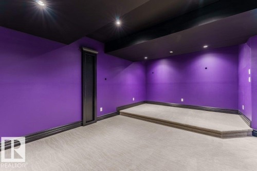 Room featuring vibrant purple walls with dark trim, recessed lighting, a raised carpeted platform, and patterned carpeting - 328 52327 Range Rd 233, Rural Strathcona County, AB 