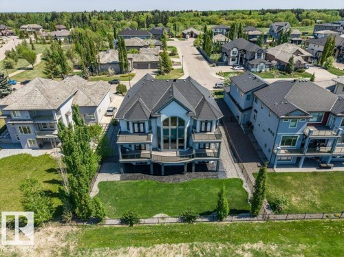 Multi-level residence featuring a prominent central arch window, multiple balconies, a dark shingle roof, and a meticulously manicured lawn - 328 52327 Range Rd 233, Rural Strathcona County, AB 