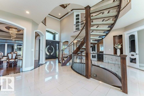 Grand foyer featuring a curved staircase with wood newel posts and wrought iron balusters - 328 52327 Range Rd 233, Rural Strathcona County, AB 