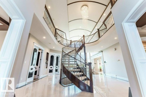 Grand foyer with a spiral staircase featuring dark wood newel posts and metal balusters - 328 52327 Range Rd 233, Rural Strathcona County, AB 