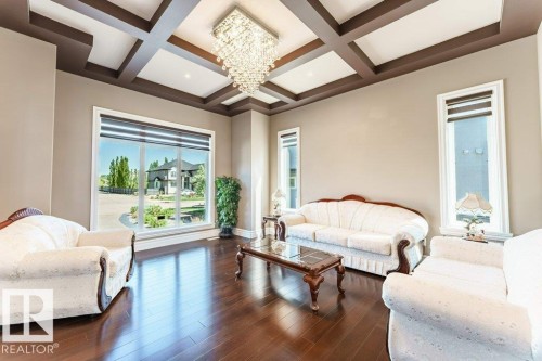 Spacious room featuring a coffered ceiling with a crystal chandelier, expansive window, two vertical windows, and dark wood-finish flooring - 328 52327 Range Rd 233, Rural Strathcona County, AB 
