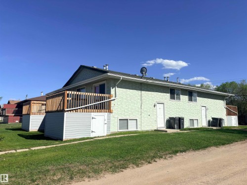 Multi-unit residence featuring a light green textured exterior and a dark shingle roof - 4537 50 Avenue, Cold Lake, AB 