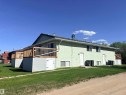 Multi-unit residence featuring a light green textured exterior and a dark shingle roof - 4537 50 Avenue, Cold Lake, AB 