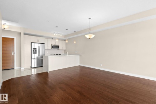 Open-concept living space with dark wood-finish flooring - 309 625 Leger Way, Edmonton, AB 