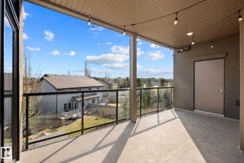 Expansive covered balcony featuring concrete flooring, a glass and metal railing, and recessed ceiling lighting - 309 625 Leger Way, Edmonton, AB 