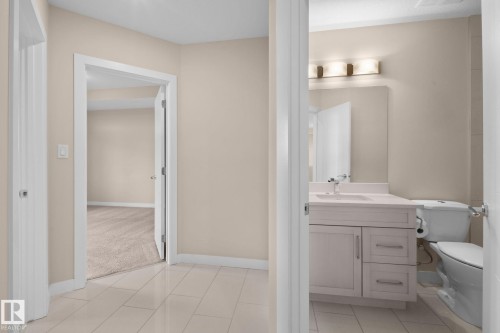 Hallway featuring light-toned tile flooring, neutral wall paint, white baseboards, and white door casings - 309 625 Leger Way, Edmonton, AB 