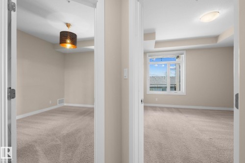 Two carpeted rooms featuring neutral wall tones and white trim - 309 625 Leger Way, Edmonton, AB 