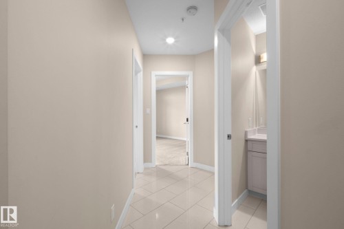 Hallway featuring neutral-toned walls, tile flooring, and recessed lighting - 309 625 Leger Way, Edmonton, AB 