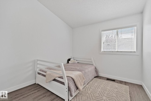 Bedroom featuring wood-finish flooring, a white window frame with blinds, and white baseboards - 1 Hunt Court, St. Albert, AB 