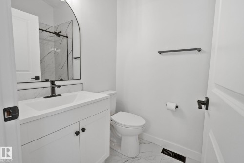 Bathroom featuring a white vanity with integrated sink, black matte faucet, and matching hardware - 1 Hunt Court, St. Albert, AB 