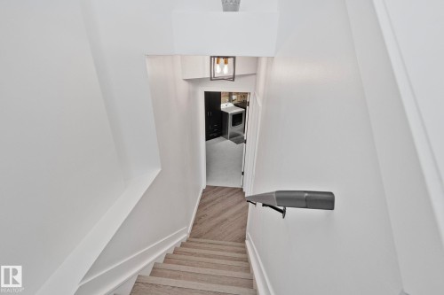 Staircase featuring wood-finish flooring, white risers, and a contemporary wall-mounted handrail - 1 Hunt Court, St. Albert, AB 