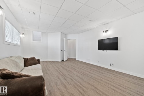 Spacious room featuring wood-finish flooring, white walls, and a grid panel ceiling with recessed lighting - 1 Hunt Court, St. Albert, AB 