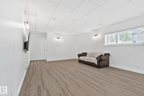 Spacious room featuring wood-finish flooring, crisp white walls, and a white grid-pattern ceiling - 1 Hunt Court, St. Albert, AB 