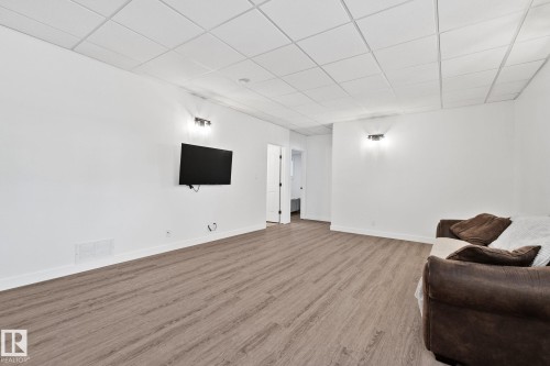 Spacious room featuring wood-finish flooring, white walls, and a grid panel ceiling - 1 Hunt Court, St. Albert, AB 