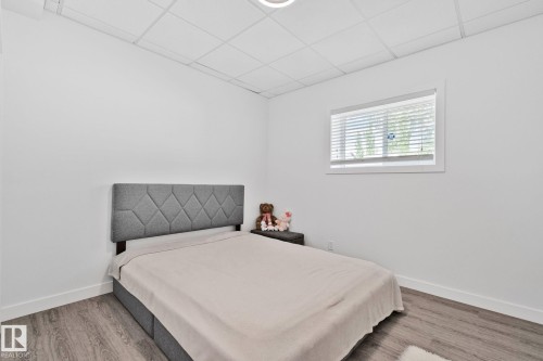 Bright room featuring a single window with blinds, wood-finish flooring, white walls, and a white drop ceiling - 1 Hunt Court, St. Albert, AB 