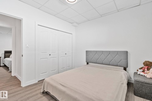 Bedroom featuring wood-finish flooring, white walls, and a drop-tile ceiling - 1 Hunt Court, St. Albert, AB 