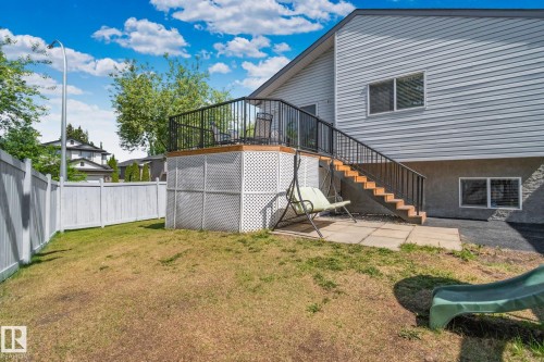 Rear exterior featuring a raised wood deck with black metal railing, lattice skirting, and an attached staircase - 1 Hunt Court, St. Albert, AB 