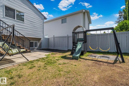Expansive rear yard featuring a privacy fence, mature trees, and a ground-level patio with stone pavers - 1 Hunt Court, St. Albert, AB 